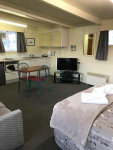 a living room with a table and a kitchen at Lantern Court Motel in Reefton