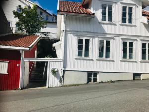 a white house with a red door next to a street at A Noi Rooms in Kragerø