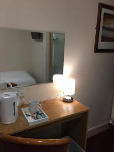 a room with a desk with a lamp and a mirror at Terra Nova Hotel in Aberdeen