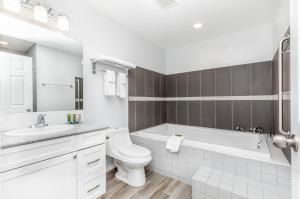 a white bathroom with a tub and a toilet and a sink at Westridge Motor Inn in Osoyoos