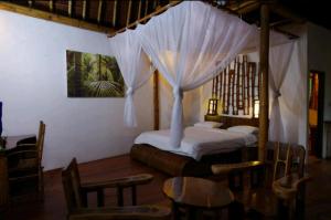 a bedroom with a canopy bed with a table and chairs at Bali Eco Village in Plaga