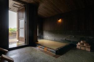 a bath tub in a room with a large window at Ryokan Nanjoen in Minamioguni