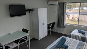 a room with a bed and a desk and a tv at Harrington Village Motel in Harrington