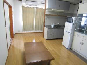 an empty kitchen with a table and a refrigerator at Marugame Guest house Wellkame in Marugame