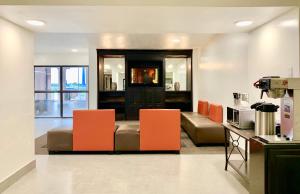 uma sala de estar com cadeiras laranja e um sofá em Motel 6-Lewisville, TX - Medical City em Lewisville