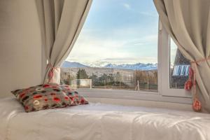 a bed with a pillow in front of a window at Cabañas Aluen in El Calafate