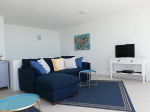 a living room with a blue couch and a tv at La Dolce Vita in Lagoa