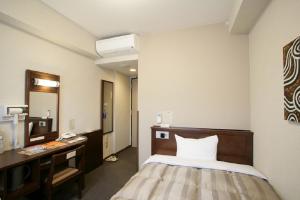 a hotel room with a bed and a desk and a mirror at Hotel Route-Inn Kanda Ekimae in Kanda