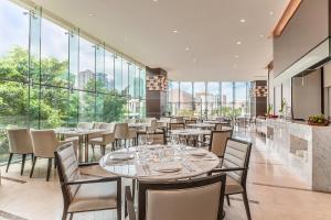 a restaurant with tables and chairs and large windows at Ascott Bonifacio Global City Manila in Manila