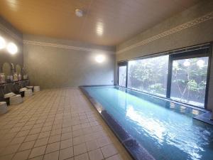 a swimming pool in a room with a large window at Hotel Route-Inn Wakamiya Inter in Miyawaka