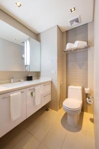 a white bathroom with a toilet and a sink at Citadines Salcedo Makati in Manila +10 photos