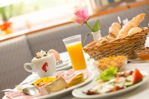 una mesa con platos de comida y un vaso de zumo de naranja en Topmotel, en Oberegging