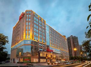 un edificio alto con ventanas de cristal en una calle de la ciudad en Hampton by Hilton Guangzhou Dongxiaonan en Cantón