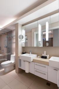 a bathroom with two sinks and a toilet and a mirror at Citadines Salcedo Makati in Manila