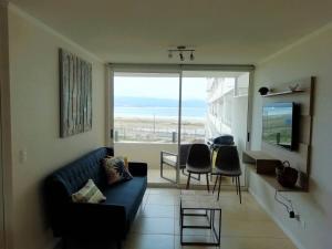 a living room with a couch and a table with chairs at Moderno departamento, inmejorable vista al mar in Los Molles