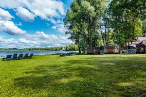 a park with chairs on the grass next to a lake at Sventes Rasa in Kaķīši