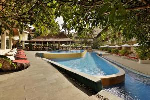 a swimming pool in a resort with chairs and umbrellas at Blu-Zea Resort by Double-Six in Seminyak