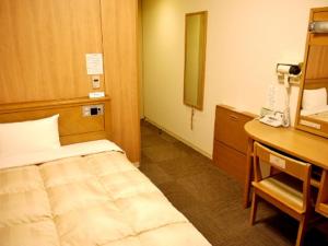 Habitación con cama y escritorio con teléfono. en Hotel Route-Inn Tomakomai Ekimae en Tomakomai