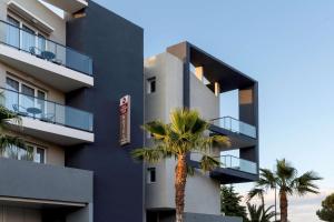 a building with palm trees in front of it at Best Western Plus Antibes Riviera in Antibes