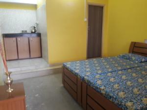 a bedroom with a bed and a kitchen in the background at Vamoose D'souza in Darjeeling