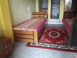 a bedroom with two beds and a red rug at Vamoose D'souza in Darjeeling