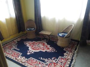 a room with chairs and a rug on a floor at Vamoose D'souza in Darjeeling