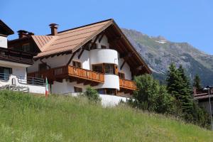uma casa numa colina com uma montanha ao fundo em Aparthotel Alpin Life em Sankt Anton am Arlberg
