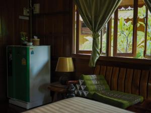a room with a refrigerator and a chair and a window at Baan Kong Homestay in Phra Nakhon Si Ayutthaya