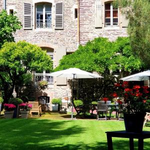 a garden with tables and umbrellas in front of a building at Castel Jolly in Rennes