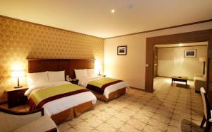 乌兰巴托Sunjin Grand Hotel的一间酒店房间，配有两张床和一张沙发