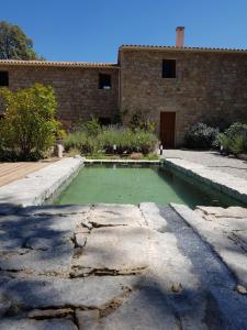 une piscine d'eau verte devant un bâtiment en briques dans l'établissement Maison d'Hôtes Zella, à Bains de Guitera