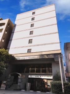 a tall white building with a door in front of it at Hotel Route-Inn Kitamatsudo Ekimae in Matsudo