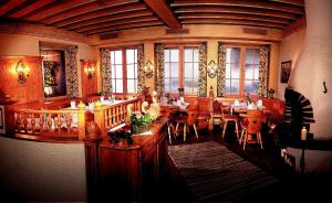 a restaurant with wooden tables and chairs and windows at Aldranser Hof in Innsbruck