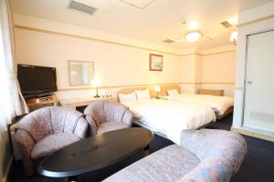 a hotel room with two beds and a table and chairs at Hotel Nature Nagoya Sakae Kishu Railway Group in Nagoya