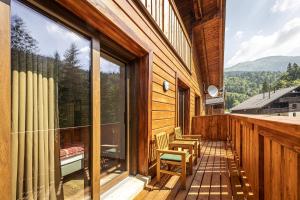 einen Balkon mit Stühlen und ein großes Fenster zum Haus in der Unterkunft Apartmánový dom Poludnica - Chopok Juh in Tale