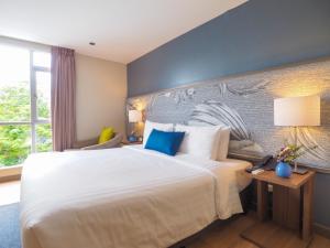 a bedroom with a large white bed with blue pillows at Asoke Residence Sukhumvit by UHG in Bangkok