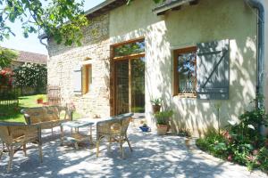 a patio with a table and chairs next to a building at Gîte des quatre chemins in La Vineuse