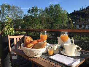 uma mesa com uma cesta de pão e dois copos de sumo de laranja em Au bord de l'eau em La Canourgue