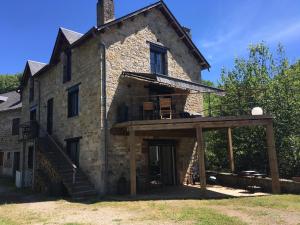 uma antiga casa de pedra com um alpendre e uma varanda em Au bord de l'eau em La Canourgue