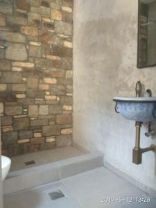 La salle de bains est pourvue d'un mur en pierre et d'un lavabo. dans l'établissement Stone built house next to the beach, à Amoliani