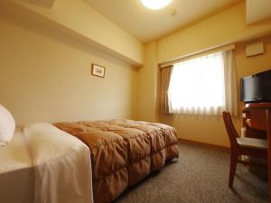 a hotel room with a bed and a window at Hotel Route-Inn Fukaya Ekimae in Fukaya