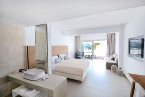 a hotel room with a bed and a bathroom at Manoula's Beach Mykonos Resort in Agios Ioannis Mykonos