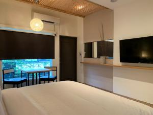 a bedroom with a bed and a table and a tv at Roppongi Motel - JianHua in Pingtung City