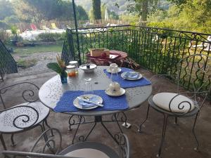 - une table avec des assiettes et de la vaisselle sur la terrasse dans l'établissement Mas des Ballats, à Saint-Bauzille-de-Putois