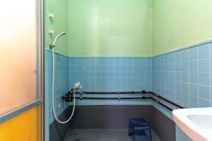 宇流麻的住宿－Deluxe Room 130平米 URUMAHOTEL，浴室的墙壁上设有蓝色瓷砖和淋浴。