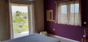 a bedroom with purple walls and a large window at Villa Fotini I in Amalias