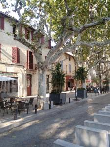a street with a tree and tables and chairs at Pause à Beaucaire avec garage à vélo ou moto in Beaucaire
