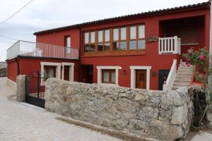una casa roja con una pared de piedra delante de ella en Casa do Bouza Vello, en Sober
