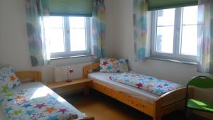 a small room with two beds and two windows at Ferienwohnung Am Verlorenen Bach in Untermühlhausen