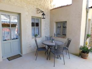 eine Terrasse mit einem Tisch, Stühlen und einer Tür in der Unterkunft La Maison Jules Goux in Mirmande
